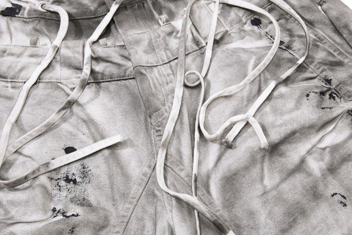 Close-up of front waistband and drawstrings on gray splatter-wash jeans