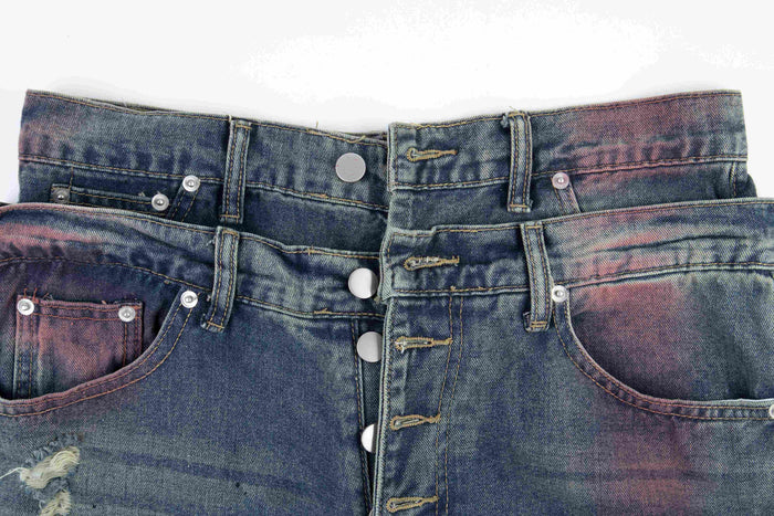 Close-up of the waistband and button fly on faded blue distressed denim jeans