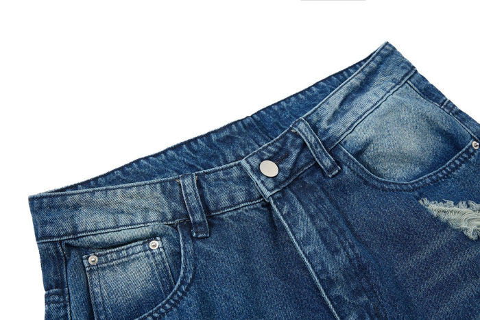 Close-up of waistband and button closure on faded blue distressed jeans