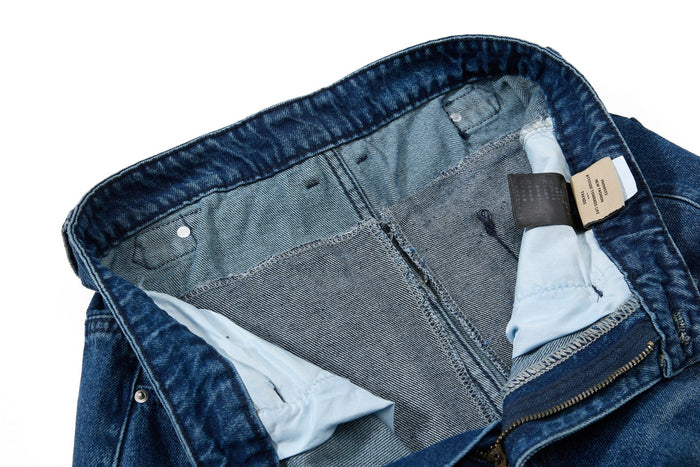 Inside waistband view of blue denim jeans with care labels and seam finish