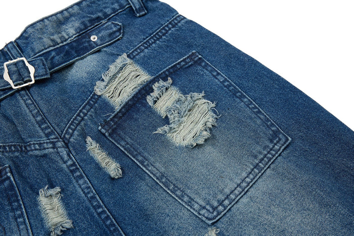 Back pocket close-up on blue jeans with frayed ripped patches and faded wash