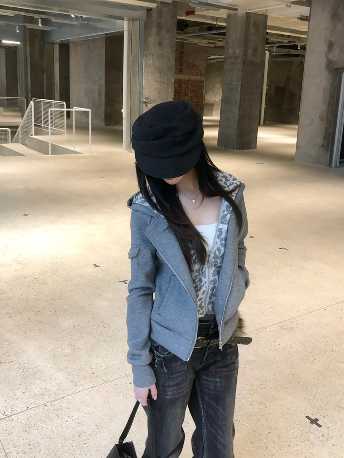 Model wearing grey hoodie with leopard-print lining and black cap