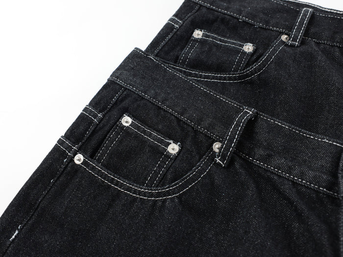 Close-up of front pocket and waist seam details on black denim pants