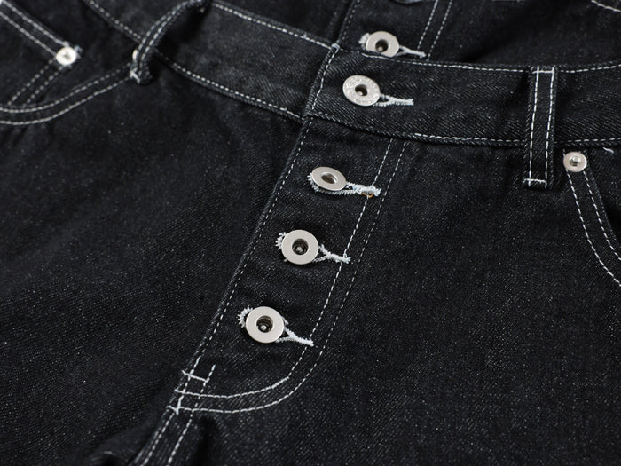 Close-up of the front button placket and seam stitching on black denim pants