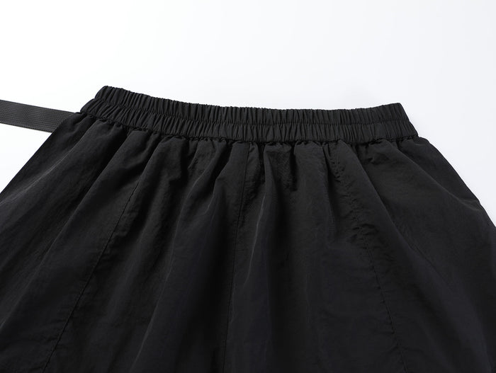 Close-up of black shorts back waistband with elastic gathering and belt end