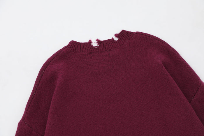 Close-up of burgundy knit sweater shoulder and torn neckline detail