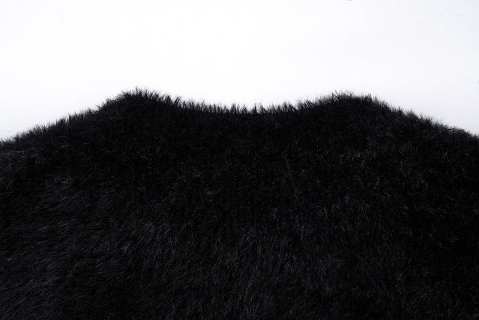 Close-up of the black sweater shoulder and upper back with fluffy knit texture