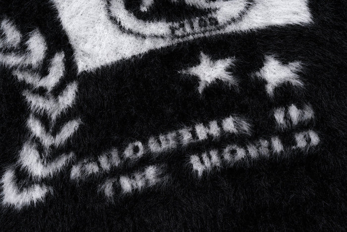 Close-up of white crest graphic details on the black fuzzy sweater