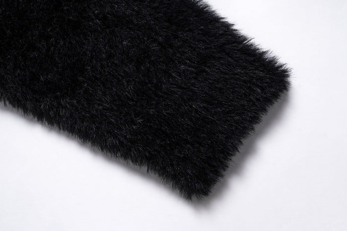 Close-up of a black fuzzy sweater sleeve cuff with plush texture