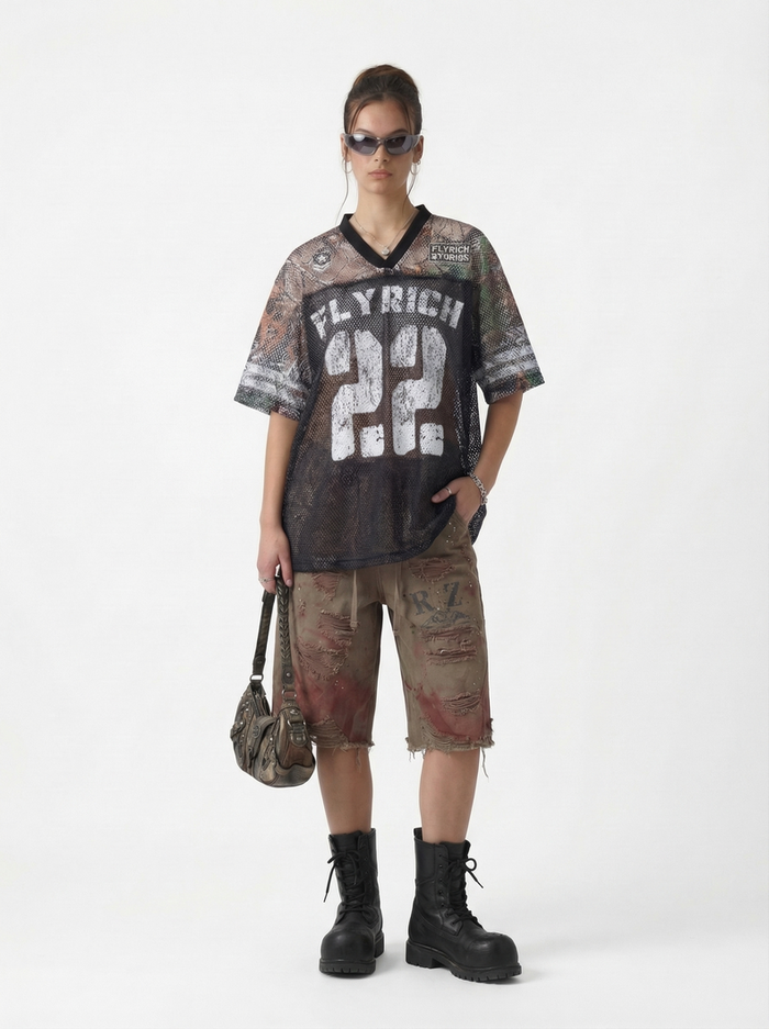 Woman wearing oversized camo mesh jersey T-shirt with bold number 22 and streetwear styling, black boots and shorts