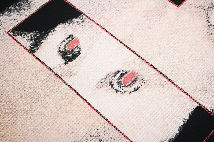 Close-up of a black streetwear T-shirt with a glitch-style cat graphic in white, pink, and black tones
