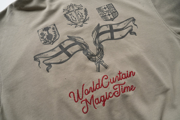 Back of taupe hoodie with black crest emblems, flag graphics, and red script text