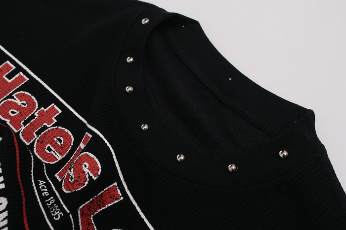 Black streetwear T-shirt with newspaper-style red and white graphic print and metal stud details