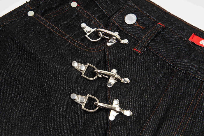 Close-up of dark wash denim front closure with three metal hook fasteners