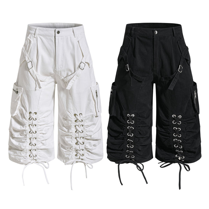 White and black lace-up utility cargo shorts with metal eyelets, ruched leg panels, and buckle hardware shown side by side
