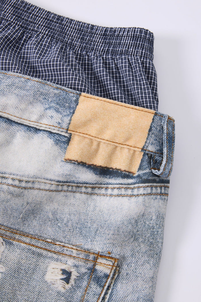 Close-up of tan patch detail at the back waistband of light wash jeans