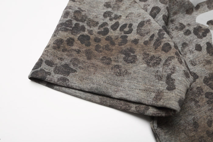 Close-up of gray leopard print oversized polo tee sleeve with stitched hem on white background