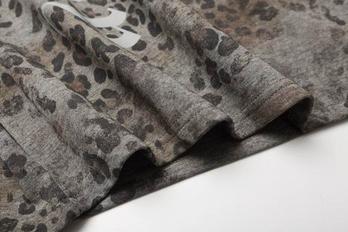 Close-up of a leopard print gothic polo tee sleeve in muted gray tones with folded oversized streetwear fabric