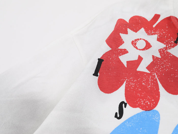 Close-up of a white graphic tee with bold red and blue streetwear print and washed, cloud-dye texture