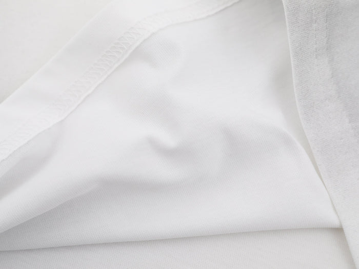 Close-up of white washed cotton tee fabric with visible stitching and soft textured folds