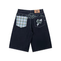 Back view of dark indigo wide-leg denim shorts with contrast plaid patch pocket and embroidered star graphic pocket