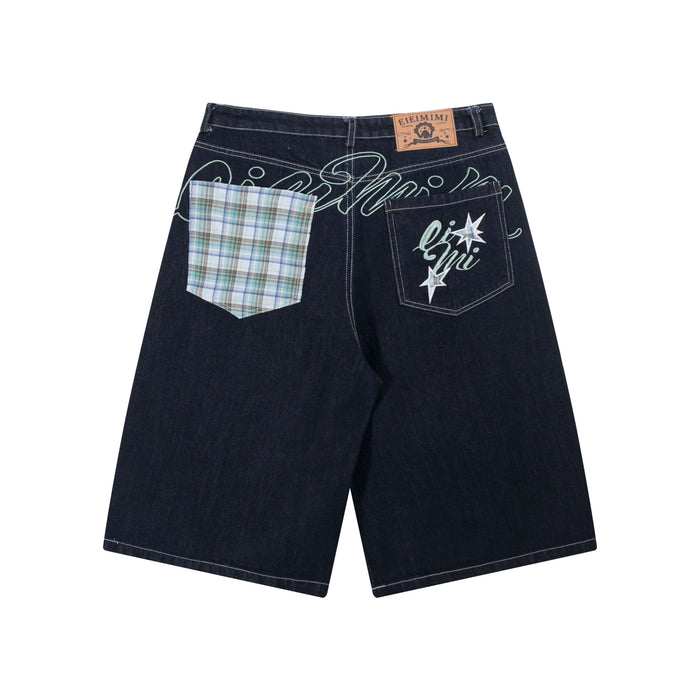 Back view of dark indigo wide-leg denim shorts with contrast plaid patch pocket and embroidered star graphic pocket