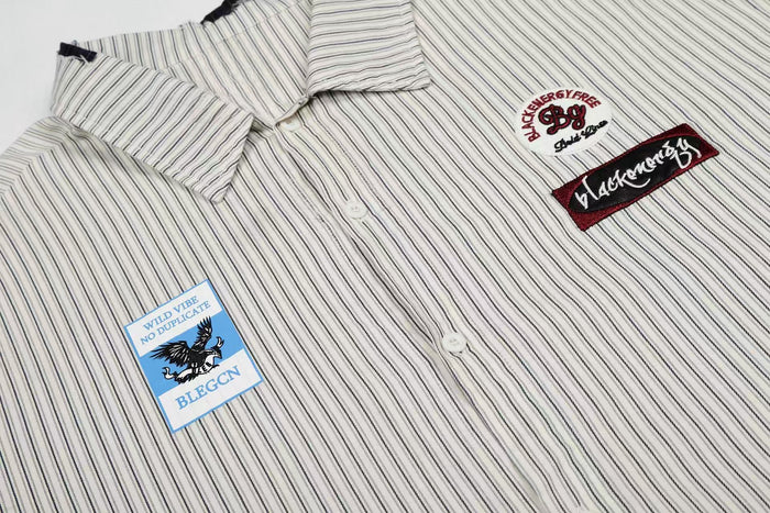 White pinstripe button-up shirt with patch graphics and embroidered streetwear details