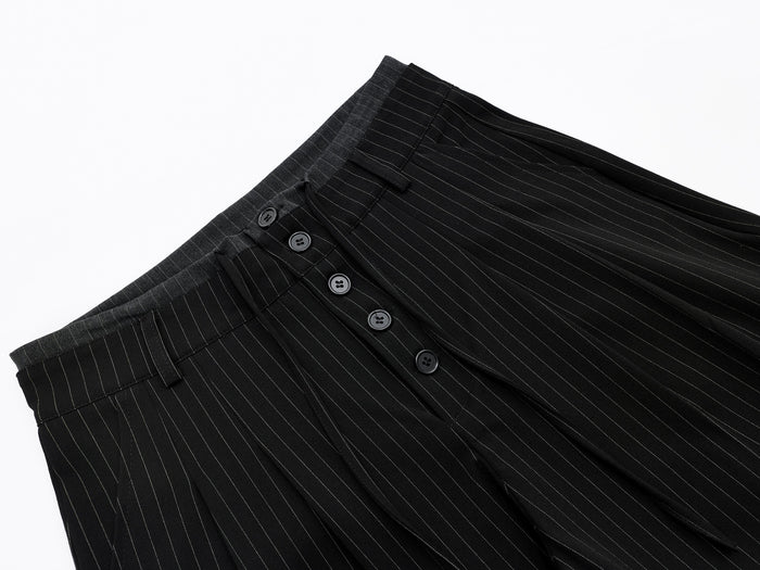 Diagonal close-up of black pinstripe shorts showing front button closure and waistband