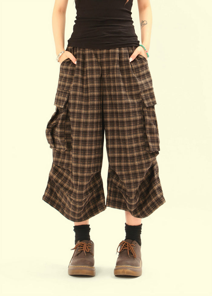 Front view of plaid knee-length cargo shorts on model with hands in pockets