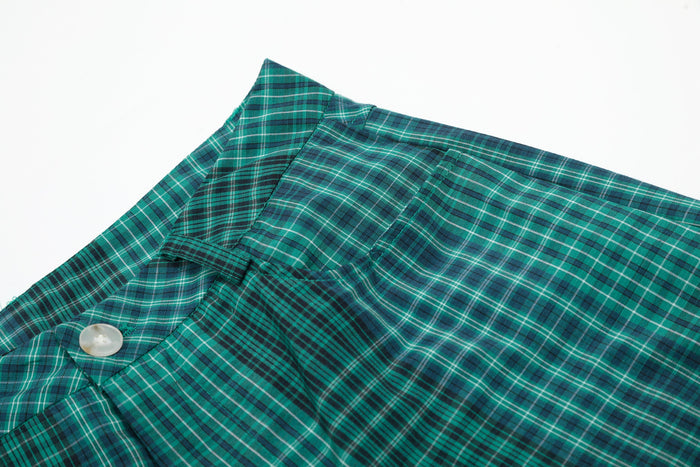 Close-up of green plaid shorts waistband and side pocket seam