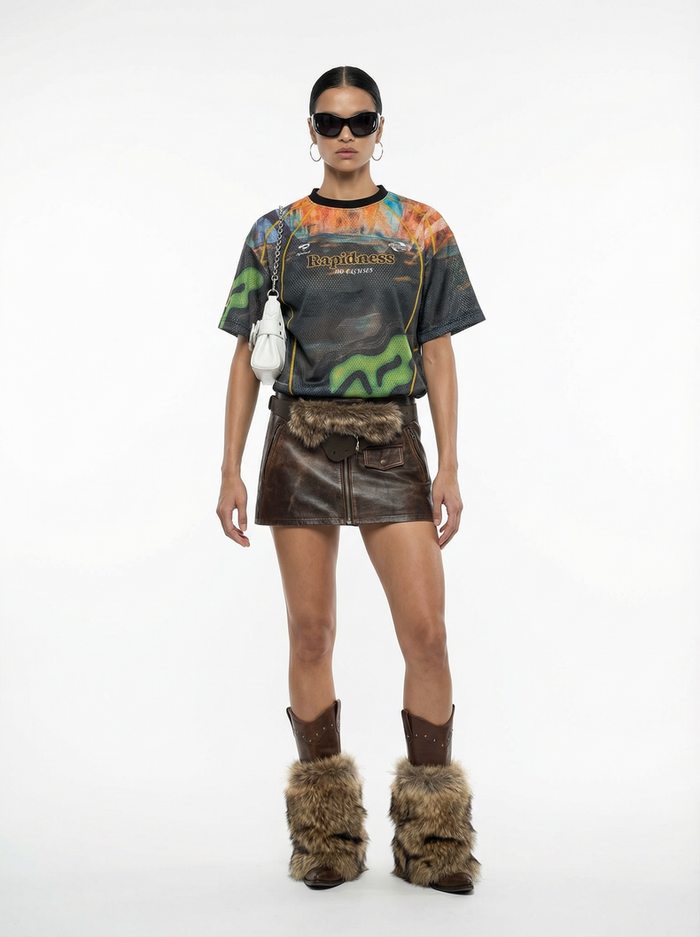 Model wearing a colorful Seakoff mesh racing jersey with graphic print, paired with a leather mini skirt and fur boots