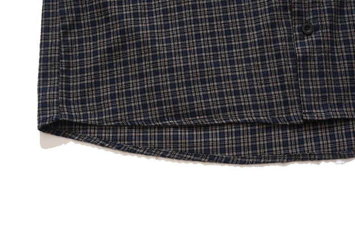 Close-up of curved hem and button front on dark plaid sleeveless shirt