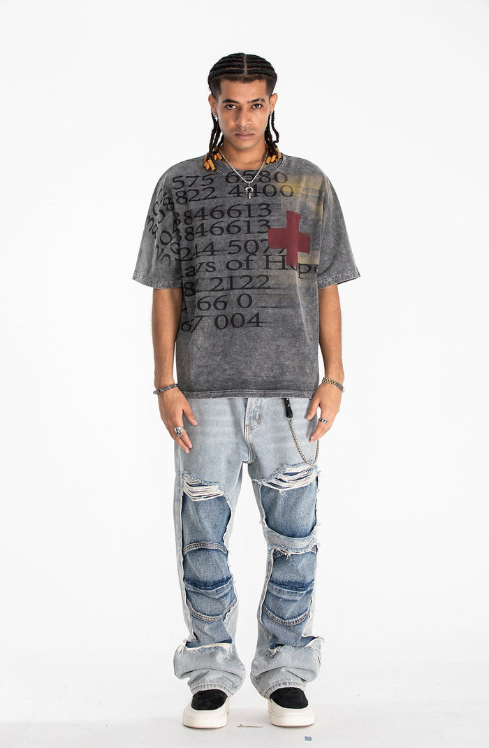 Oversized vintage wash graphic tee with abstract numbers and a red cross on a faded black-gray background