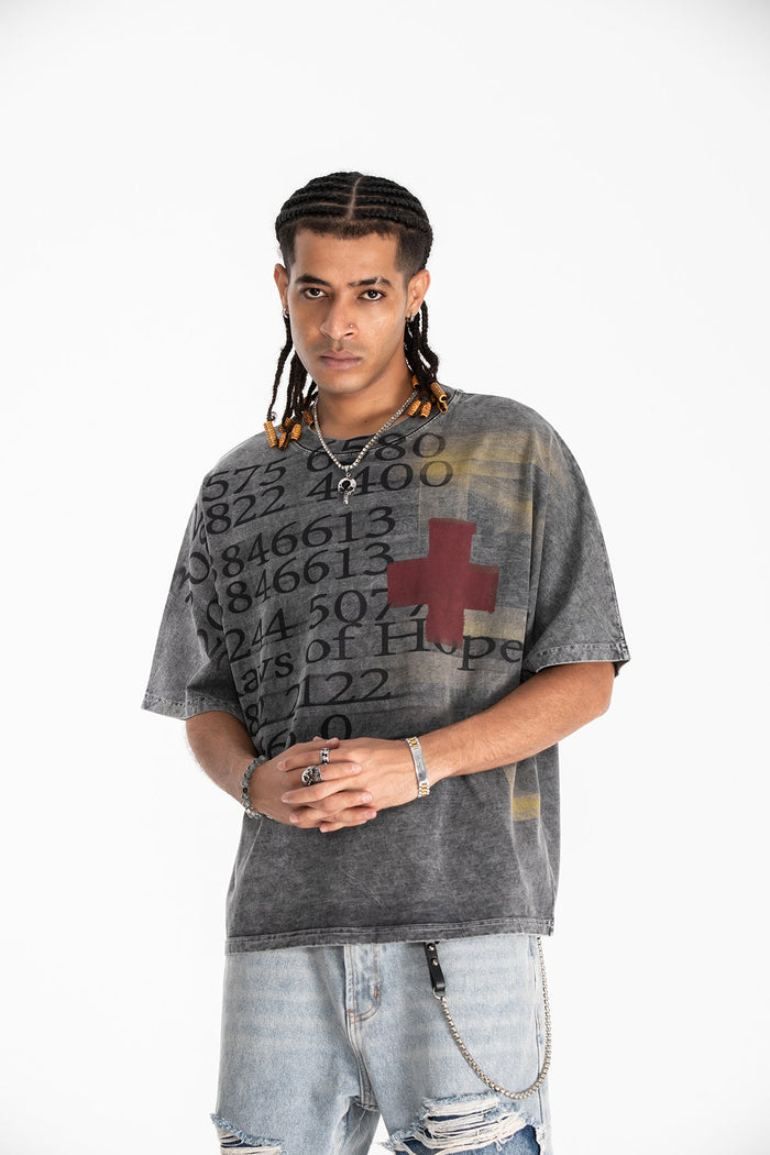 Grey vintage wash oversized graphic tee with numbers and a red cross print, styled with light ripped jeans and chains