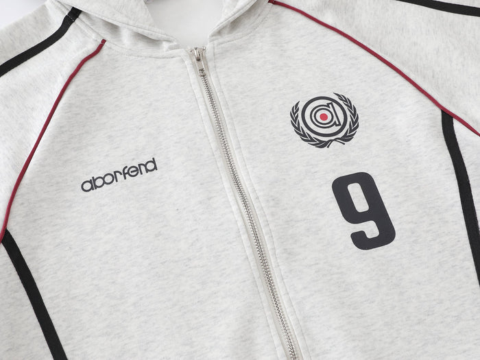 Close-up of light gray hoodie front showing zipper, chest logo, and red trim detail