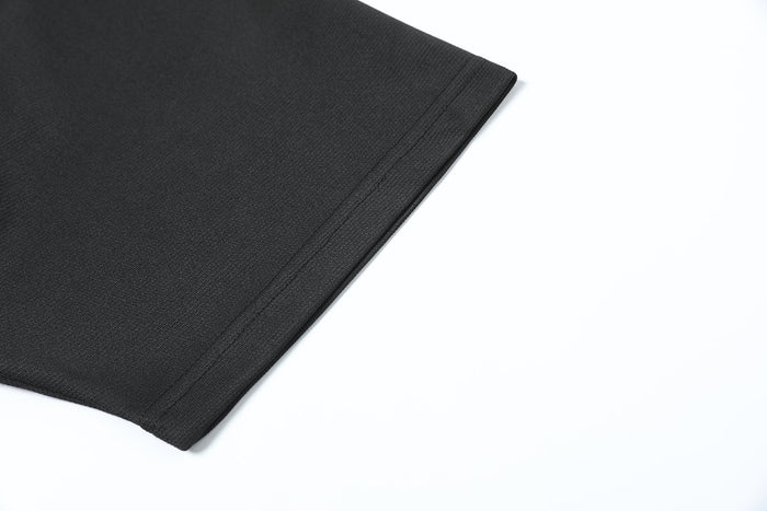 Close-up of matte black oversized tech T-shirt hem with structured stitching and textured fabric