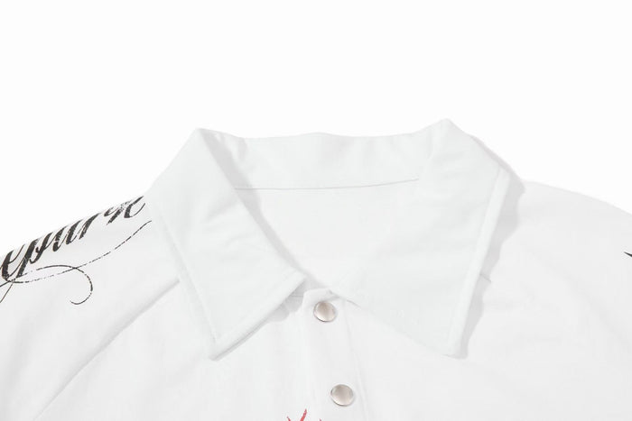 White distressed graphic polo shirt with black script print and snap buttons on a clean background