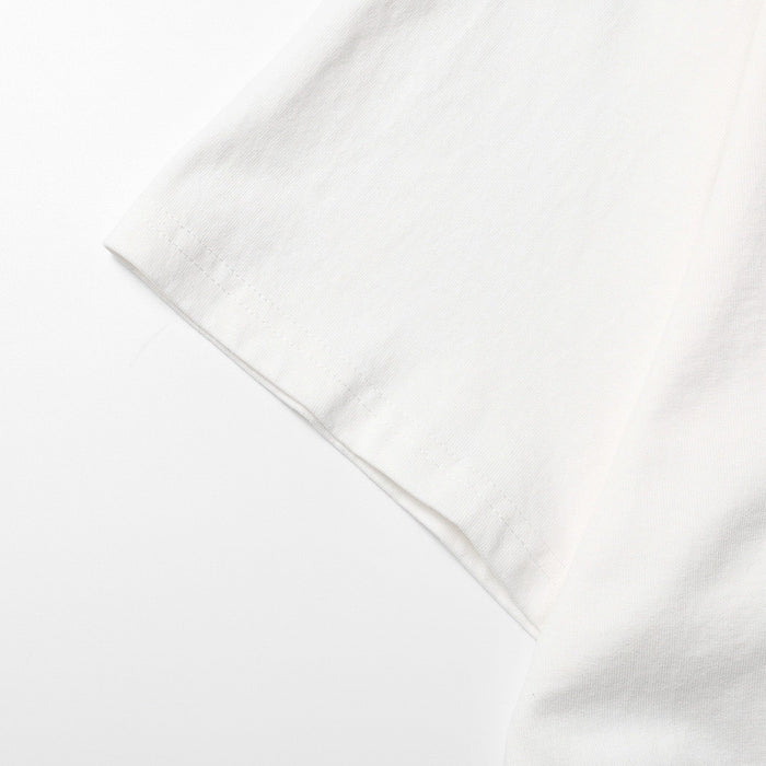 Close-up of a white oversized streetwear tee sleeve with clean hem and soft ribbed cotton texture