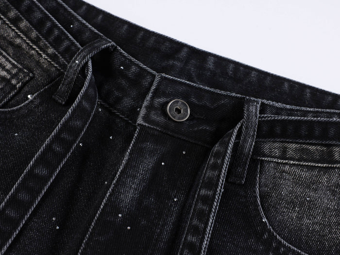 Close-up of black denim waistband with button, belt loop, and rhinestone details
