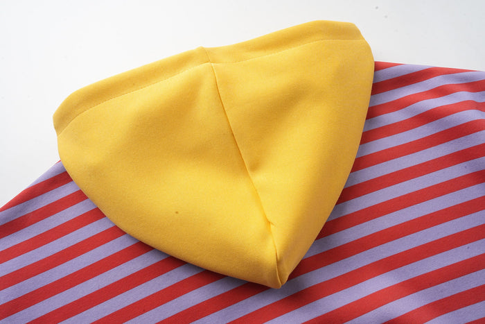 Close-up of yellow hood laid over red and lavender striped fabric