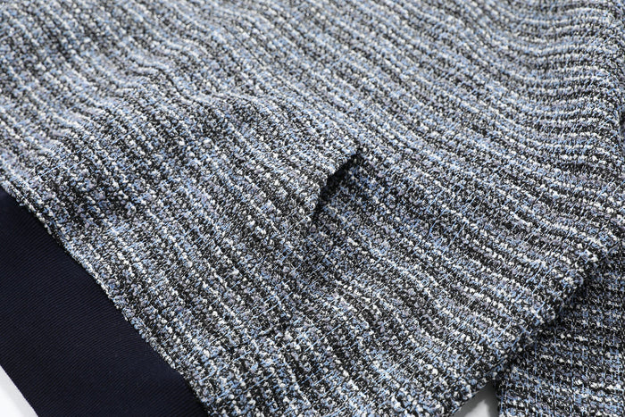 Close-up of gray and black boucle knit fabric with a small fold in the sleeve