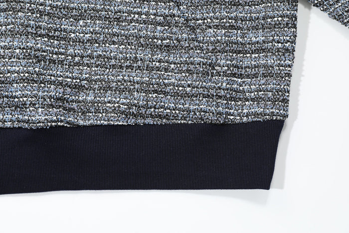 Close-up of the hoodie hem with black ribbed trim under textured knit fabric