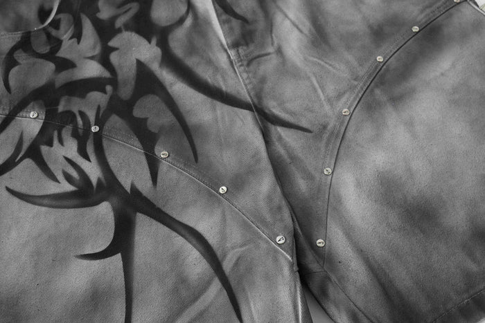 Close-up of gray jorts showing curved seam stitching and small silver studs