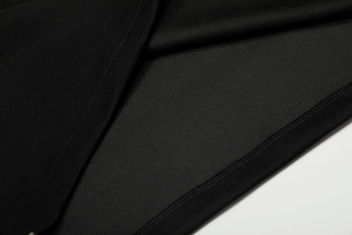 Black sweatshirt fabric close-up showing smooth knit texture and seam stitching