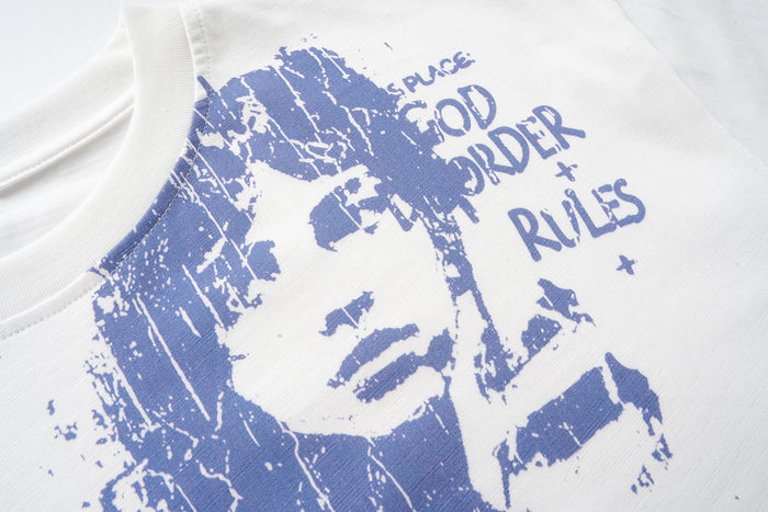 Close-up of blue face graphic and text print on the off-white tee