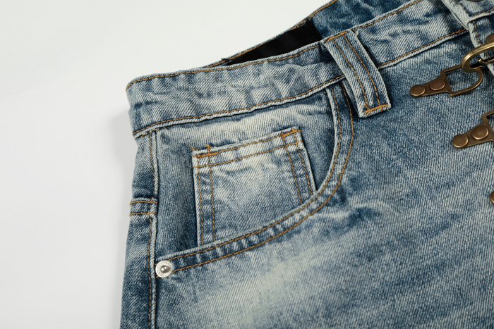 Close-up of front pocket and waistband detail on faded blue jeans with topstitching