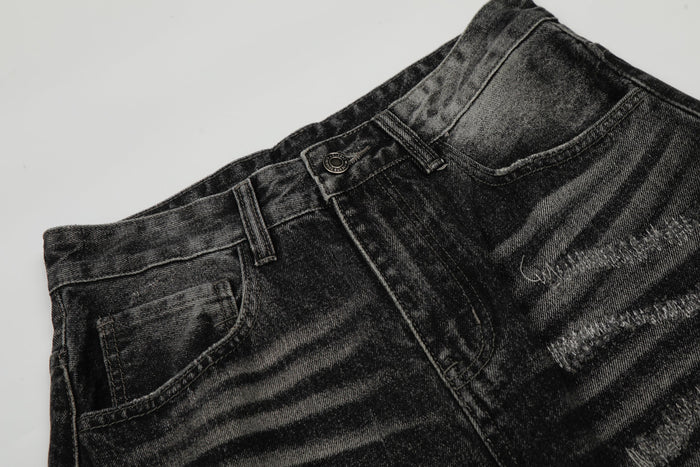 Close-up of front waistband, button, belt loops, and faded black denim texture