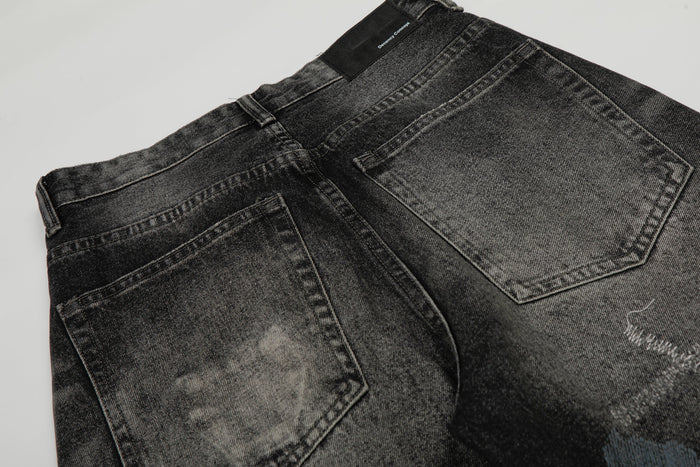 Back waist close-up of black washed denim pants showing rear pockets and brand patch
