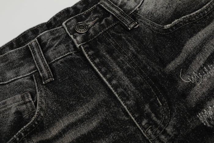 Close-up of front waistband and button on black distressed denim pants