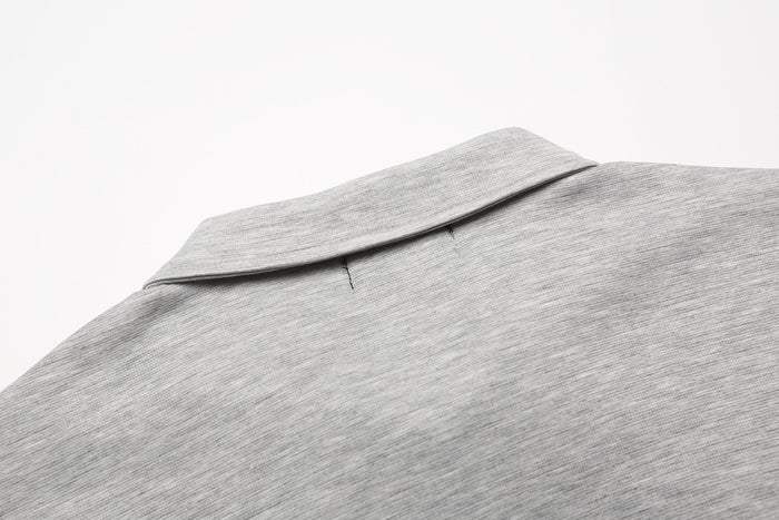 Close-up of a light gray embroidered polo shirt collar with subtle gothic detailing and soft cotton texture